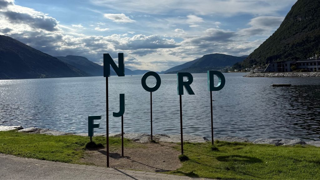 Selfie-Spot mit Nordfjord-Schriftzug in Nordfjordeid vor Bergen und Fjordlandschaft